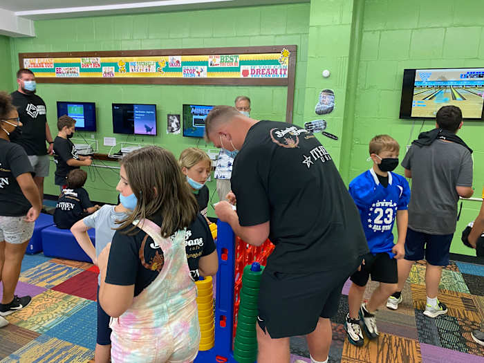 Pitt lineman Jake Kradel signs his autograph for a young fan in between games of Connect Four at the Boys and Girls Club in Millvale on Tuesday.